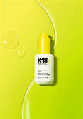 K18 hair care product bottle on a bright yellow background