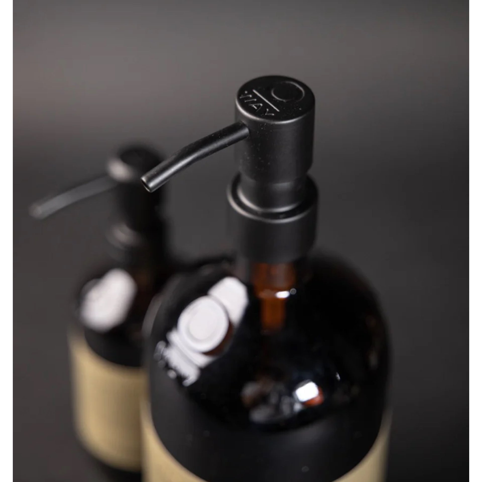 Two black bottles with pump dispensers on a dark background