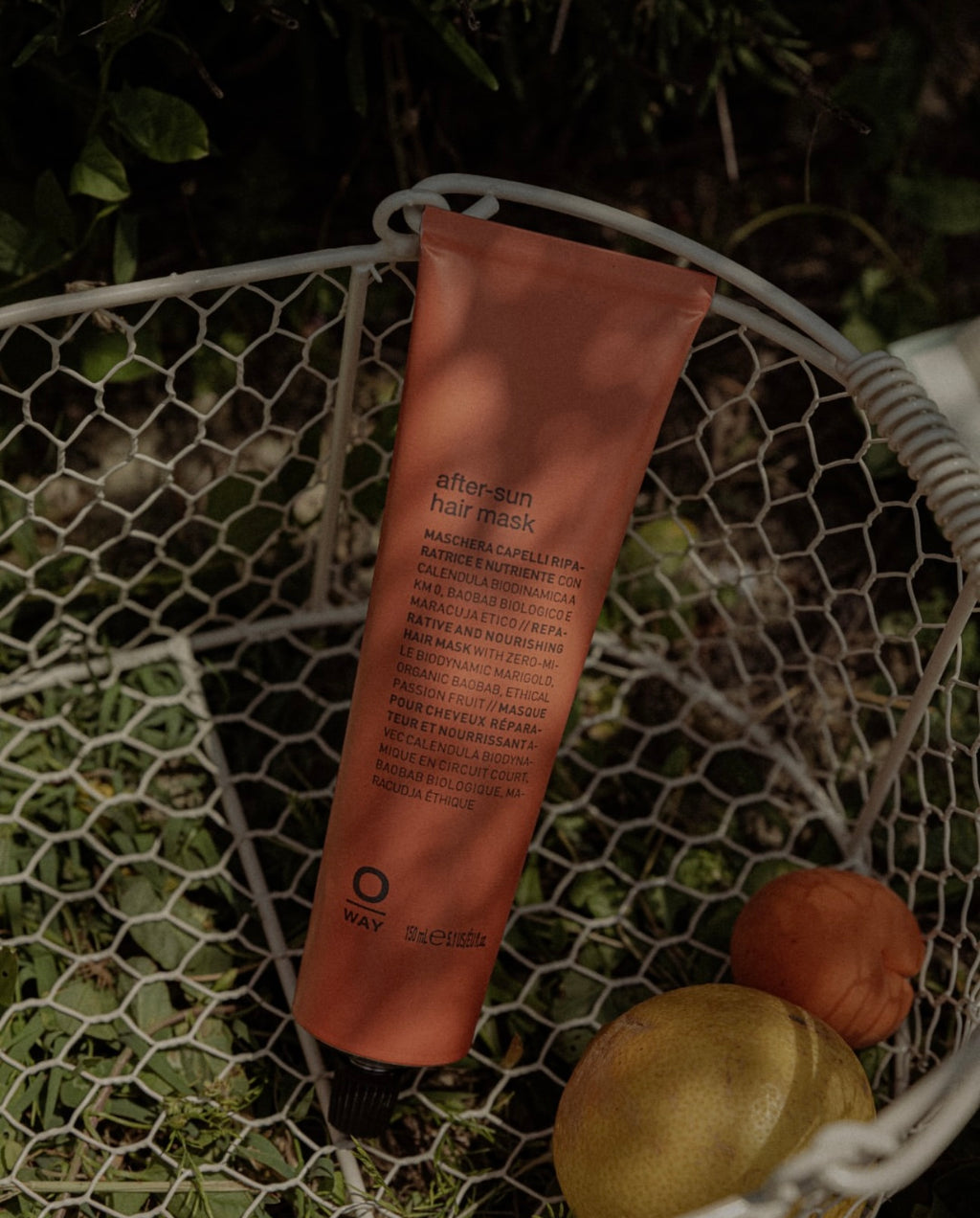 Orange Oway hair mask tube on a textured surface with greenery