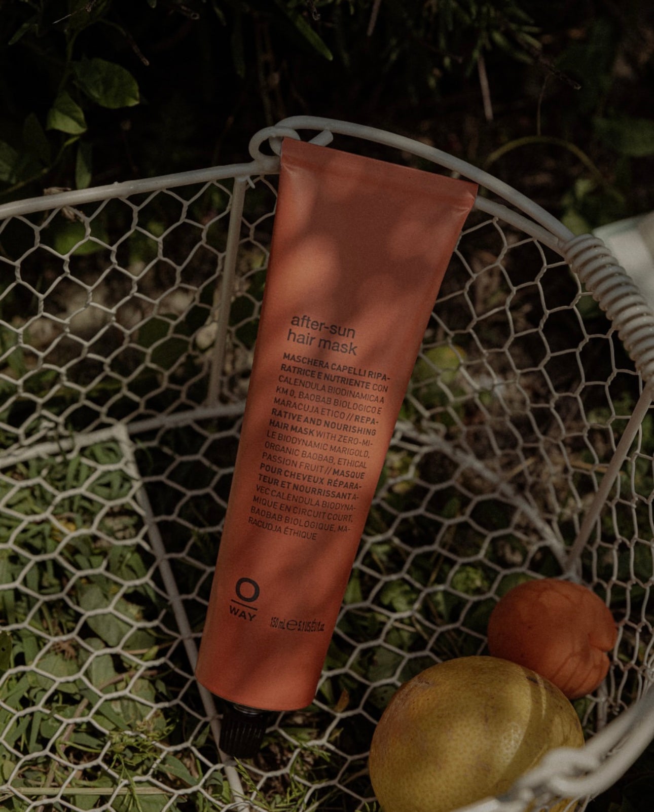 Orange Oway hair mask tube on a textured surface with greenery