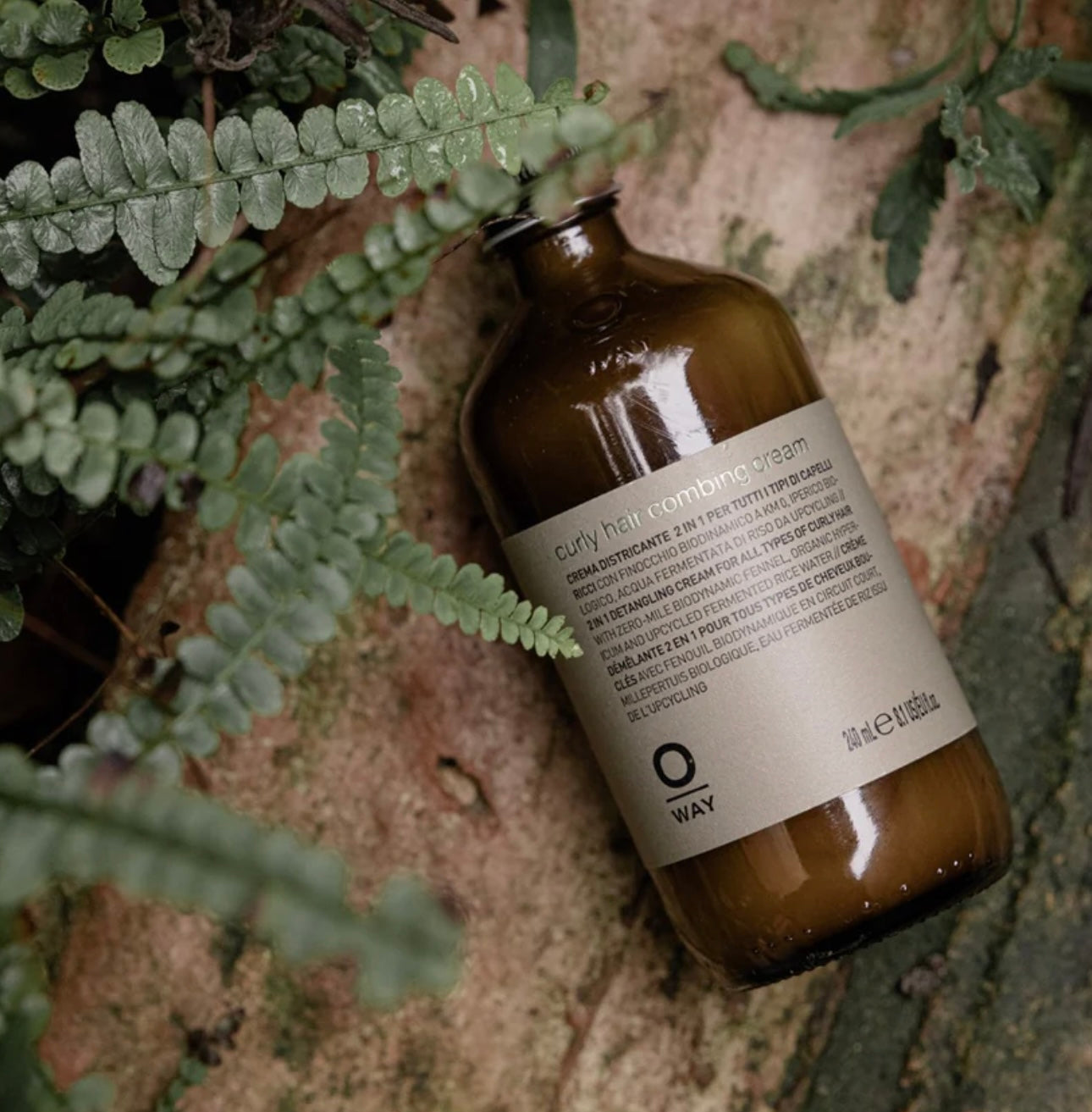Oway Brown bottle with label on a textured surface with green leaves