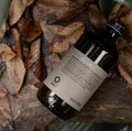 Bottle of Oway curly hair bath on a textured surface with leaves